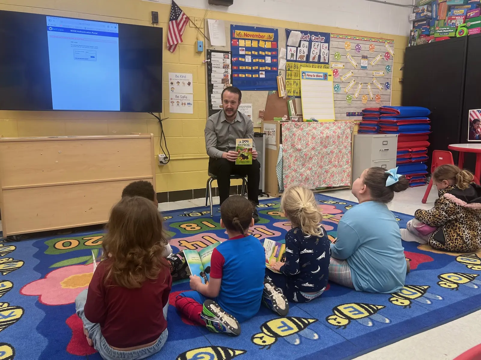 Joshua reading A Dog Named Frog with children in a colorful classroom