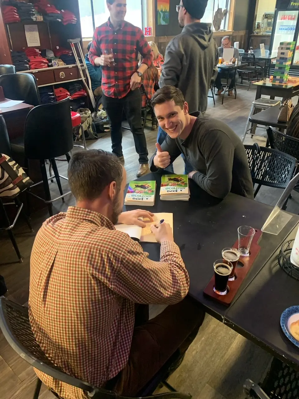 Joshua signing a copy of A Dog Named Frog for a smiling reader